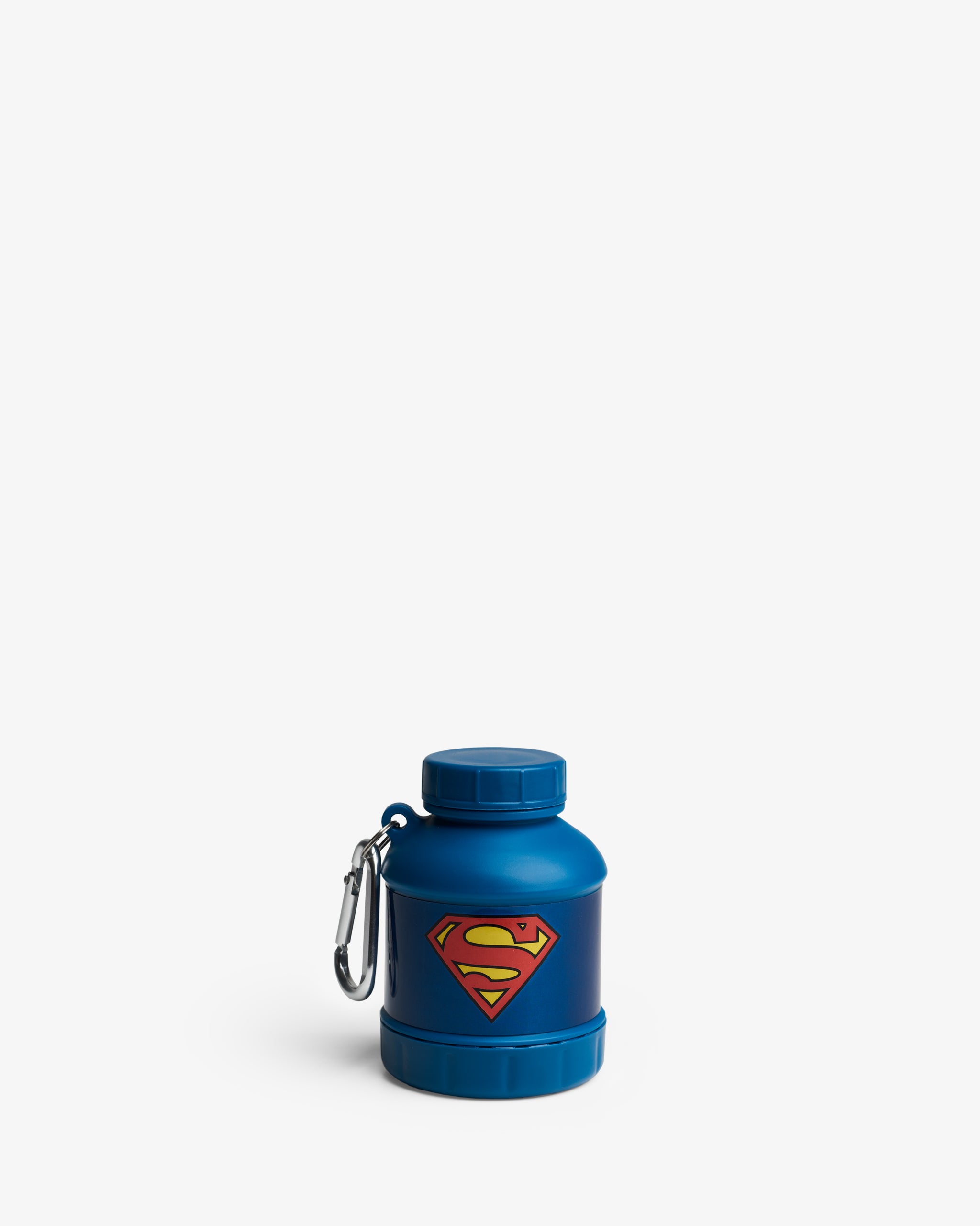 A blue portable supplement container with a Superman logo on it, equipped with a carabiner clip.